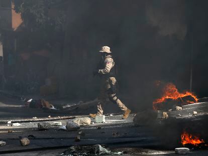 Un policía despeja una carretera bloqueada por manifestantes en el barrio Lalue de Port-au-Prince, Haití, el miércoles 14 de julio de 2021.