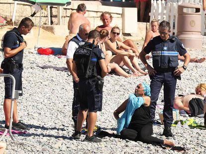 Una mujer se quita la camisa mientras la polic&iacute;a le pone una multa en Niza.