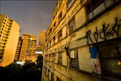 Dos jóvenes encaramados a una cornisa para pintar en un edificio de Sao Paulo.