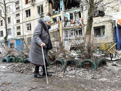 Una anciana camina ayudada por un bastón junto a su edificio, dañado por los bombardeos rusos en Járkov, este martes.