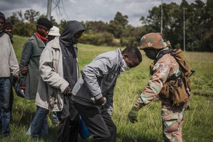 Un soldado marca la distancia en la cola de los 'sin techo' que aguardan por raciones de comida, este jueves en Johanesburgo (Sudáfrica).