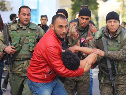Un ciudadanos y vario soldados llevan a un joven que trat&oacute; de quemarse a  lo bonzo en una protesta el viernes en Kaser&iacute;n.