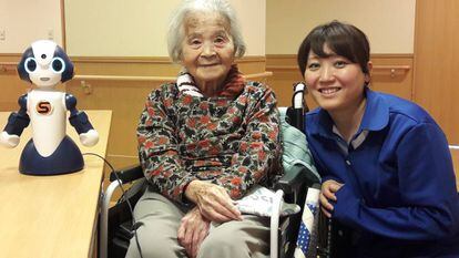 Una mujer japonesa de avanzada edad, junto a una cuidadora y el robot 'Sota', en una residencia de Tokio.