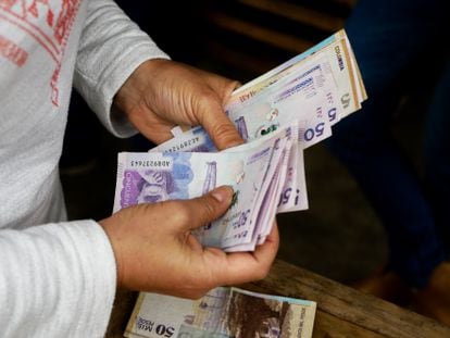 Un hombre cuenta billetes de pesos colombianos.