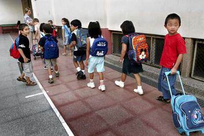 Alumnos de una escuela pública de Barcelona con sus mochilas y carteras con ruedas.