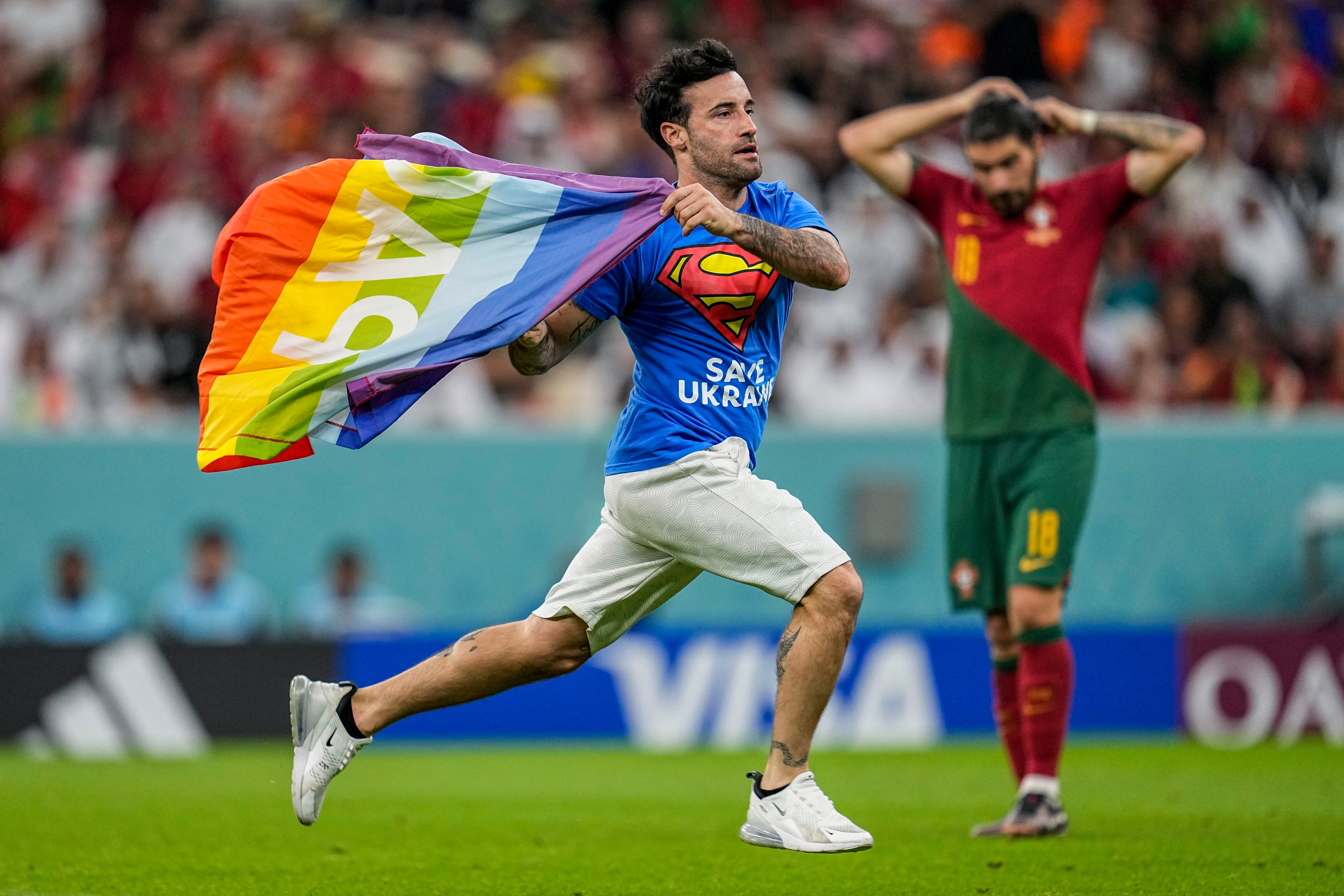 Un joven salta al campo con la bandera LGTBI.