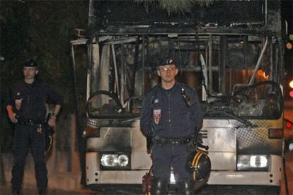 Dos policías ante el autobús incendiado anoche en Marsella
