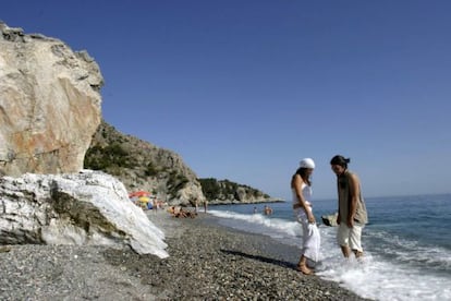 Dos jóvenes se mojan los pies en la playa de Cantarriján, naturista y natural, en Almuñecar.