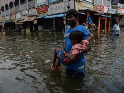 People wade through a waterlogged street at a residential area after a heavy monsoon rainfall in Chennai on November 12, 2021. (Photo by Arun SANKAR / AFP)