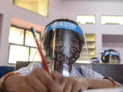 Una estudiante con mascarilla y plástico protector atiende en clase el 11 de febrero de 2022 en uno de los colegios públicos femeninos de Hyderabad, India.