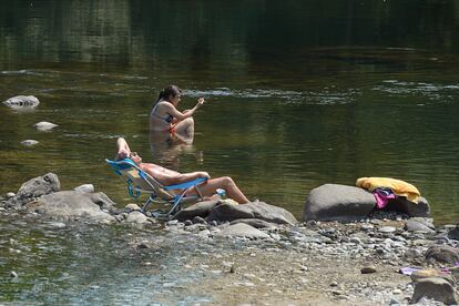 Dos personas se remojan en la orilla del río Miño, el martes en Orense. Los termómetros de la totalidad del territorio gallego alcanzaron valores “extremos” debido a la ola de calor que comenzó la semana pasada y que durará hasta el viernes 15 de julio.