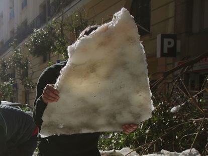 Vecinos retiran con palas el hielo de la calzada en Madrid, tras la borrasca Filomena.