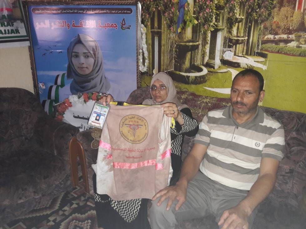 Los padres de la sanitaria palestina abatida el día 1 de junio en Gaza muestran su identificación como socorrista..