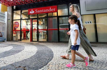 Una mujer y una ni&ntilde;a pasean frente a una sucursal del Banco Santander.