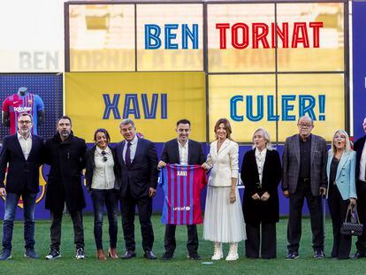 Xavi posa con una camiseta del Barça junto al presidente Joan Laporta y familiares del nuevo técnico, este lunes en el Camp Nou.