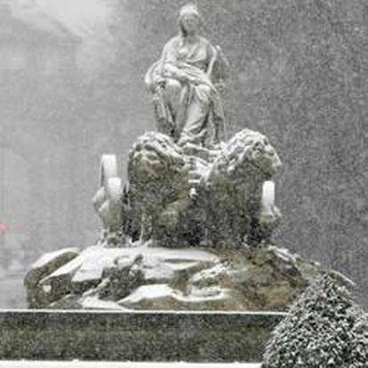 La estatua de la Cibeles con la Puerta de Alcalá al fondo durante la intensa nevada que cae hoy sobre la ciudad de Madrid