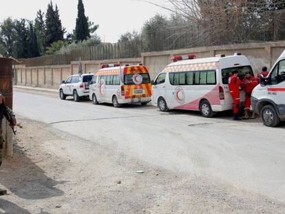 Un soldado del ejército sirio, junto a un grupo de voluntarios de la Media Luna Roja en el corredor humanitario cerca de Damasco el pasado 28 de febrero. En el vídeo, un convoy de Cascos Blancos se ve sorprendido por un ataque aéreo este lunes cerca de Guta.