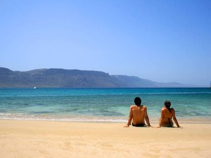 Una pareja sentada en una playa de la isla de La Graciosa (Canarias).