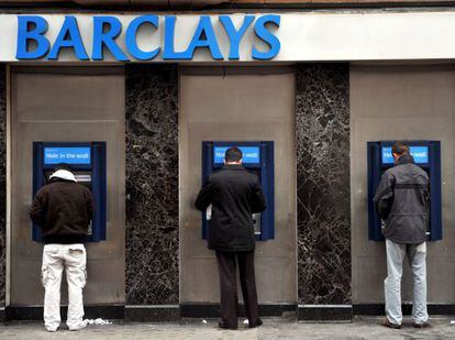 Algunos hombres retiran dinero de unos cajeros automáticos en una sucursal de Barclays Bank en Londres, Reino Unido.