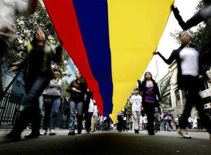 Los manifestantes sujetan una gran bandera colombiana durante la marcha en Bogotá.