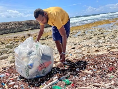 Un voluntario de Green Phenix reconoce los plásticos que la marea ha traido a la costa, en una playa de Curaçao.