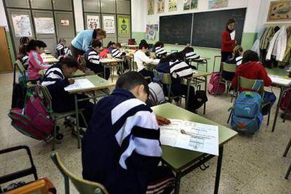 Niños valencianos atendidos por dos profesoras durante un examen.