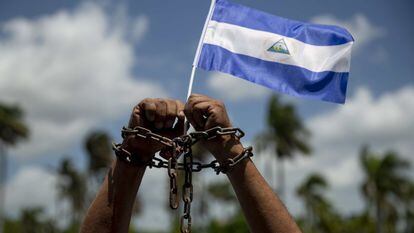 Un hombre con cadenas en las manos y una bandera de Nicaragua participa en una misa por la liberación de presos políticos.