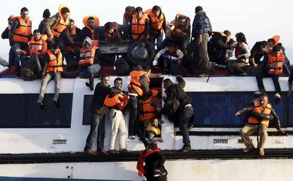 Refugiados e inmigrantes tratan de salir del barco mientras este se hunde frente a la isla griega de Lesbos.