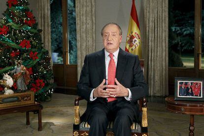 Don Juan Carlos, en un momento del discurso navideño. A la derecha, una fotografía del Monarca con los campeones del mundo de fútbol.