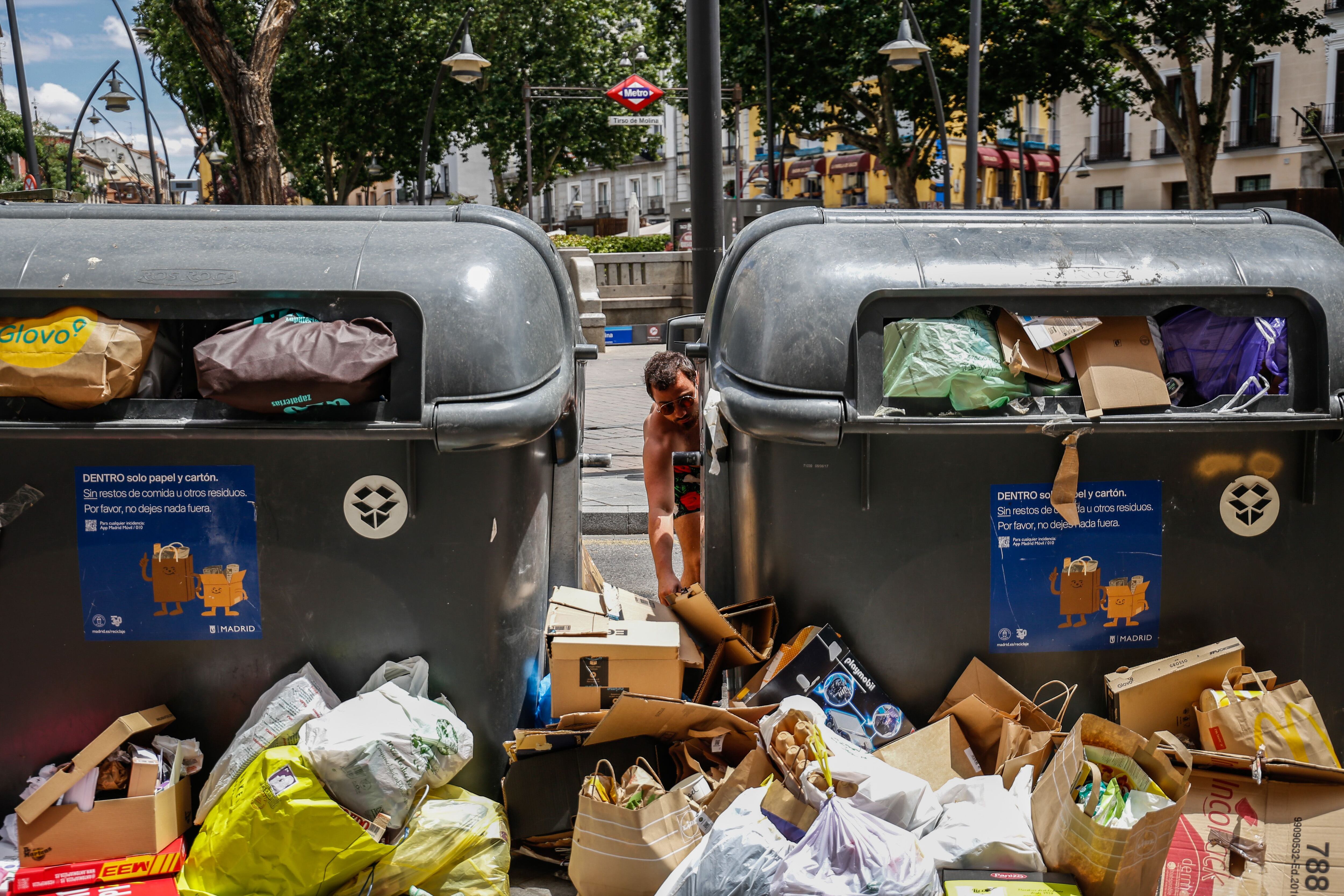 Un joven deja basura entre los contenedores de reciclaje en la plaza de Tirso de Molina de Madrid el 20 de junio.