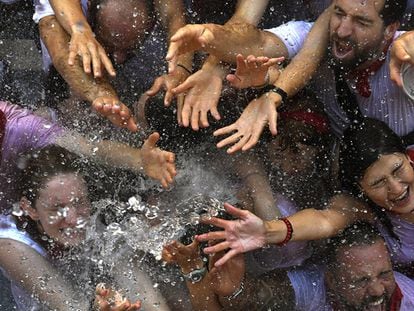 JÓvenes reciben con alivio agua desde los balcones el dÍa del Chupinazo, que da inicio a las famosas fiestas de San FermÍn.