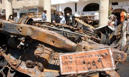 Varios transeúntes observan un coche destrozado en el mercado viejo de Sharm el Sheij.