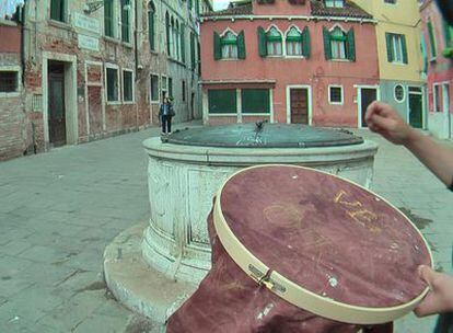 Una <i>performer</i> borda narcomensajes con hilo de oro sobre tela ensangrentada en Venecia.