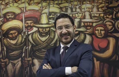 Martí Batres frente a una reproducción de un mural de Siqueiros.