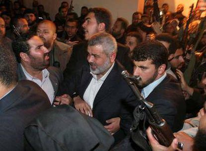 El primer ministro palestino, Ismail Haniya (centro), rodeado de guardaespaldas y simpatizantes a su llegada anoche a su casa en Gaza.