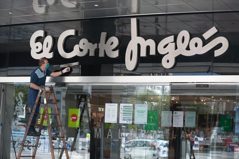 Un trabajador limpiando una entrada de una tienda de El Corte Inglés en Málaga.
