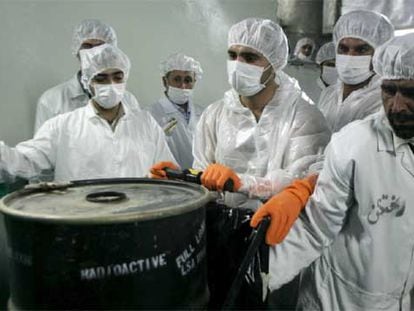 Técnicos nucleares iraníes, junto a un bidón con productos radiactivos ayer en la central nuclear de Isfahán.