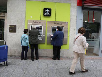 Personas mayores sacan dinero en un cajero de Bankia durante el inicio de la semana octava del estado de alarma decretada por la crisis del coronavirus