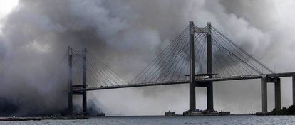 Vista del puente de Rande envuelto en humo del incendio de Fandicosta.