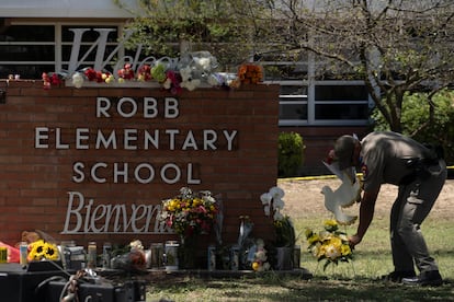 A police officer places flowers at the entrance to Robb Elementary School in Uvalde, Texas, on May 25, 2022.