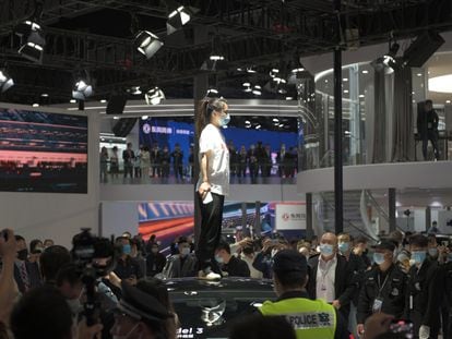 Una mujer protesta contra Tesla subida en un vehículo de la marca en el Salón del Automóvil de Shanghai.