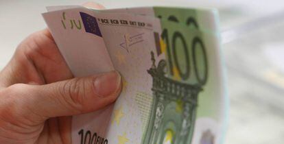 Una persona sostiene billetes de 100 euros. 