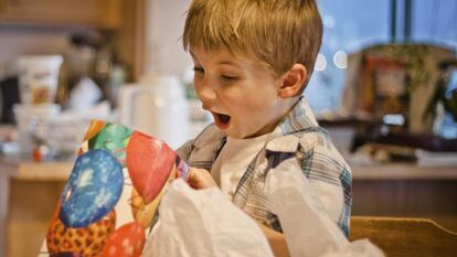 Un niño abre un regalo en Navidad.