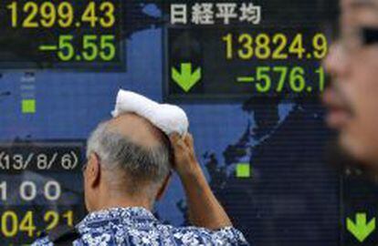 Un viandante pasa por delante de una pantalla que muestra la cifra alcanzada por el &iacute;ndice Nikkei de la Bolsa de Tokio.