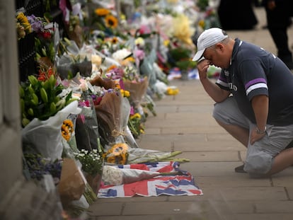 People react as they place flowers and tributes Buckingham Palace in London on September 9, 2022, a day after Queen Elizabeth II died at the age of 96. - Queen Elizabeth II, the longest-serving monarch in British history and an icon instantly recognisable to billions of people around the world, died at her Scottish Highland retreat on September 8. (Photo by Daniel LEAL / AFP)