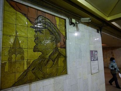 Una mujer pasa cerca de una cámara de seguridad situada junto a un mosaico de Lenin en una estación de metro de Moscú.