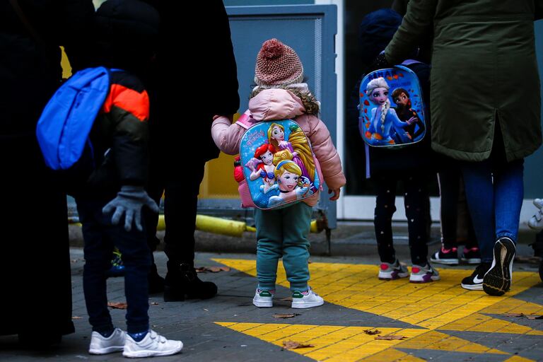 Varios niños esperan para entrar en una escuela tras las fiestas de Navidad.