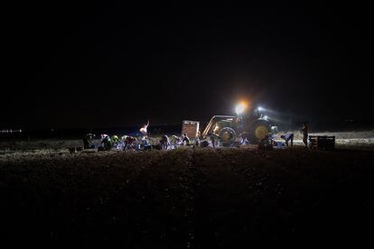 Un grupo de trabajadores, alumbrados por un vehículo y sus propias linternas.