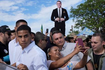 President Bolsonaro poses with an admirer for a portrait Monday at the New Jerusalem rural workers' settlement in Brasilia.
