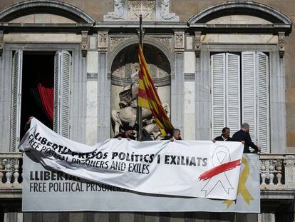 Trabajadores del Palau colocan una pancarta encima de la ya existente con el mismo lema pero con un lazo blanco tachado con una raya roja.